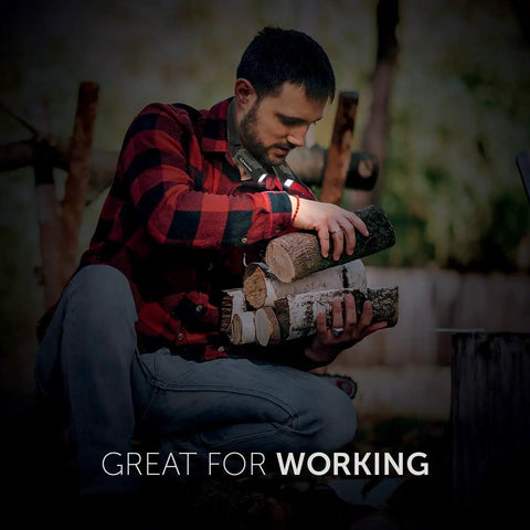 Man wearing Real Tree 300 Lumen Hands Free Neck Light With Red And White LEDs, carrying firewood outdoors.