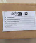 Cardboard box with assembly instructions label in multiple languages, featuring recycling symbol and safety icons.