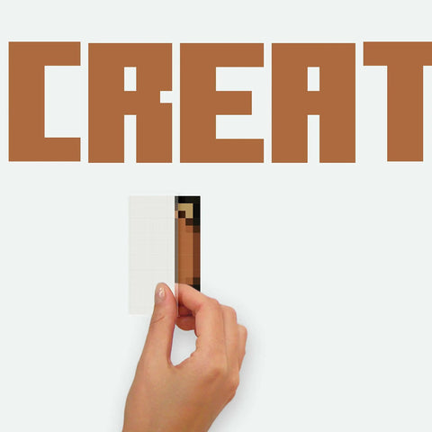 Hand applying Minecraft Eat Sleep Mine Create Peel And Stick Wall Decal Set on smooth surface, showing partial design.