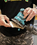 18V Cordless 1/4 Sheet Finishing Sander With Two Speed Control 11K And 14K OPM held in hand, changing abrasive paper