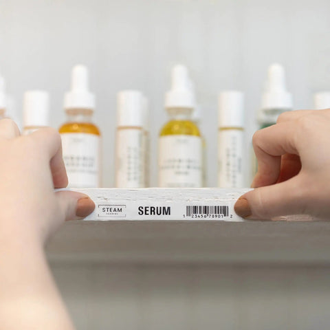 Person placing labeled shelf with "SERUM" tag using Pro Grade P-Touch PT-D610BTVP Connected Label Maker, bottles behind.