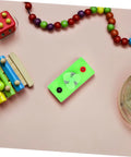 Green Solar Powered DC Motor DIY Kit Wind Turbine Generator For Science Projects on pink background, surrounded by beads.