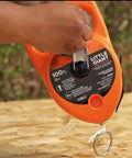 Pro Grade Chalk Line Reel With 110 Foot Reach, 12 Ounce Chalk Capacity, visible on a wooden surface, gloved-hand friendly grip.