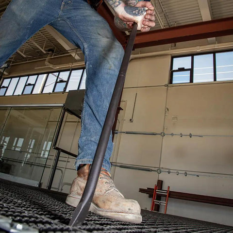 Worker using Round Three Quarter Inch Thirty Inch Connecting Bar With Fifteen Degree Angled Chisel End For Easy Alignment Prying And Chiseling Made In USA Sleever Bar on metal grating.