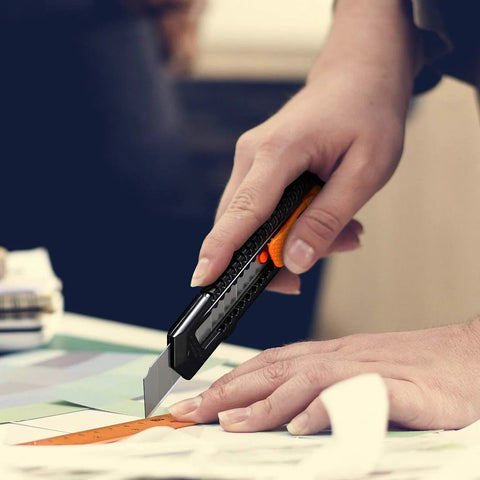 REXBETI retractable utility knife with orange thumb slider cutting cardboard.