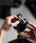 Hand adjusting the Game Changing 58mm Espresso Portafilter Station, a sturdy metal accessory for baristas.