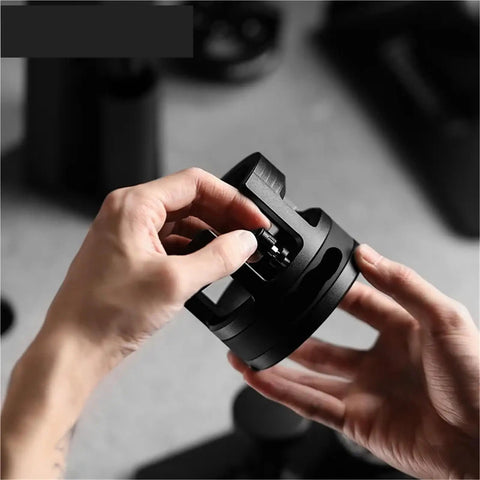Hand adjusting the Game Changing 58mm Espresso Portafilter Station, a sturdy metal accessory for baristas.