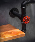 Close-up of industrial iron pipe wine rack for home bar flex with red valve and wooden shelf detail, heavy duty storage solution.