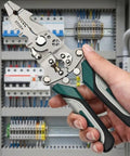 Hand holding Foldable Multifunctional Wire Stripper And Pliers Set With Crimper And Side Cutter in front of electrical panel