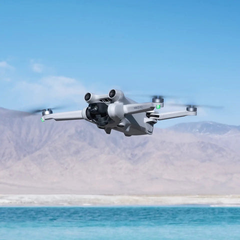 Ultra Light Mini 3 Pro Drone With 4K Video And 48MP Photos flying over a lake with mountains in the background, showing its aerial capabilities.