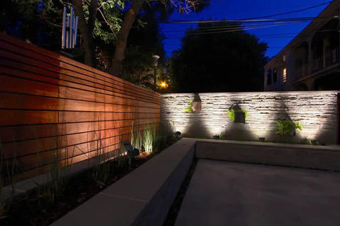 Sun Powered 4 LED Solar Spotlight Kit, 2 Pack, illuminating a garden wall at night, demonstrating landscape lighting effect.