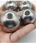 Stainless steel piercing replacement balls with M6 threaded holes, chrome spherical beads held in hand (close-up view)