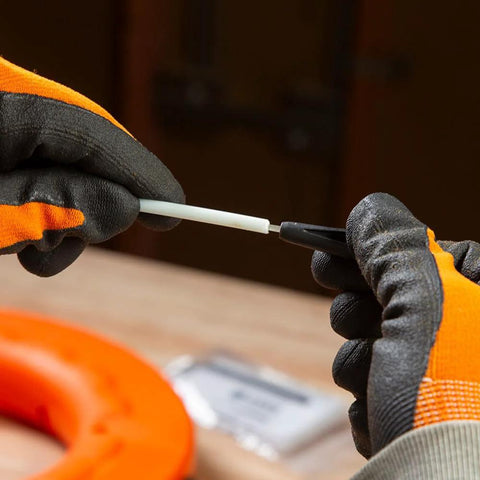 Non-conductive fish tape repair kit; white tape with black connector, held by orange-gloved hands.