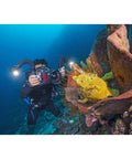 Diver using Underwater Photo And Video Lighting Kit With 5000 Lumen Dragon Head, Color Boost, illuminating coral reef.