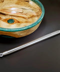 Carbide woodturning tool with long metal handle, for turning acrylic/resin on a wood lathe, shown beside a wooden bowl.