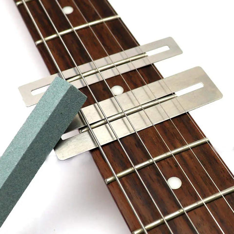 Guitar Luthier Tool Kit with fingerboard guards and grinding stone on guitar fretboard for precise fret work setup and maintenance.