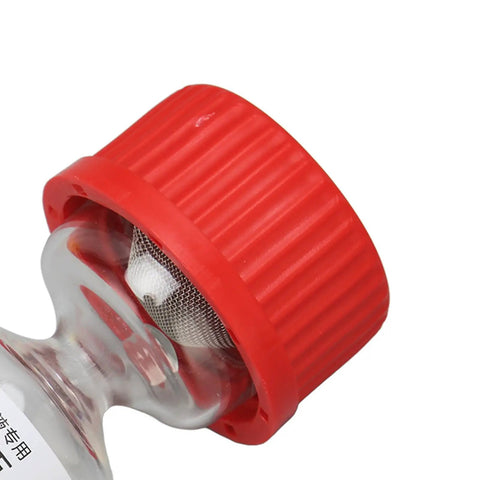 Close-up of red cap on evaporating glass bottle for watch repair precise lubricant application and diffusion prevention.