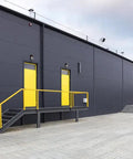 Yellow doors on a modern black warehouse exterior with steps and railing, suitable for 7 Inch Mini LED Wall Pack Outdoor Light Fixture use.