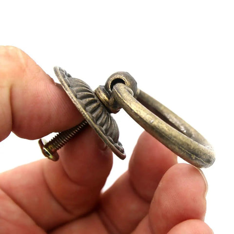 Close-up of Vintage Antique Brass Ring Pull Handle showing round disk shield, thick ring, and zinc alloy material in hand.