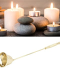 Slick Stainless Steel Candle Snuffer With Ergonomic Long Handle And Hassle Free Wick Control For Tapered Dinner Candles And Fresh Home Decor Setup In Classic Gold Finish placed amidst candles and stones.