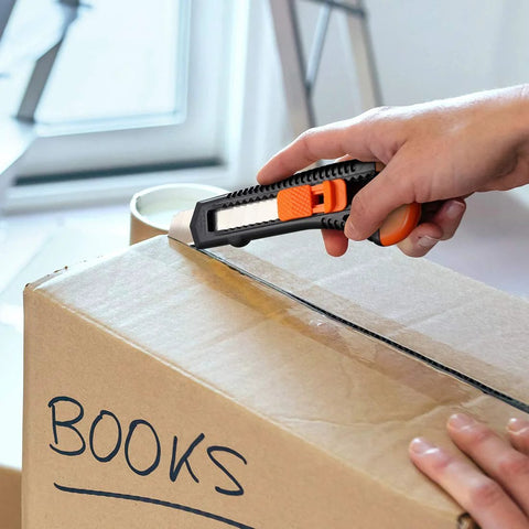 Rexbeti 12-pack retractable utility knife (orange/black) cutting open a cardboard box