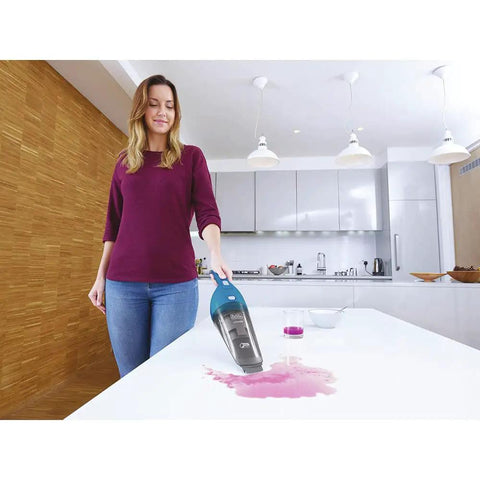 Woman using Cordless Handheld Vacuum For Home And Car Cleaning, Lightweight Grab-And-Go Dustbuster on kitchen counter spill