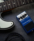 CP-1X Compressor Guitar Pedal With Next-Gen MDP Tech next to a guitar and cables on a dark surface.