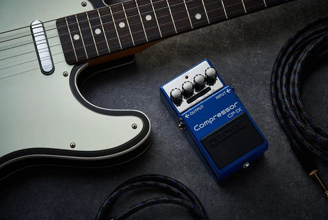 CP-1X Compressor Guitar Pedal With Next-Gen MDP Tech next to a guitar and cables on a dark surface.
