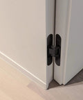 Invisible 5.5 Inch 3 Way Adjustable Concealed Door Hinges Matte Black Zinc Alloy 180 Degree Swing Hidden Butt Hinge For Doors 38mm To 60mm Thick 66 Lb Per Hinge No Fuss Vertical Horizontal And Depth Adjustments No Visible Hardware installed on white door corner.