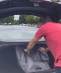 Man placing Built Tough Heavy Duty Storage Tote Bag 22 Gallon Rugged Woven Polypropylene Moving Bag into car trunk.