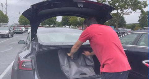Man placing Built Tough Heavy Duty Storage Tote Bag 22 Gallon Rugged Woven Polypropylene Moving Bag into car trunk.