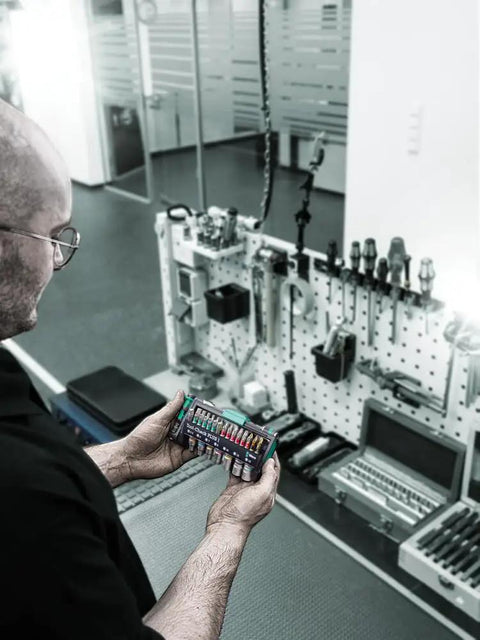 Person holding Multicolor Tool Check Plus 1 Style Kit By Wera Tools Pro Grade For Pros And DIYers in a workspace.