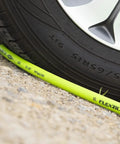 Close-up of ZillaGreen air hose under tire, demonstrating durability. Air Hose Half Inch By 100 Feet Heavy Duty Lightweight Hybrid.