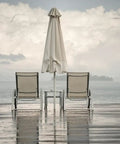 Two lounge chairs with umbrella on wet patio, illustrating Water Shield Outdoor Fabric Spray For Gear And Patio Furniture, 10.5 Ounces Water Repellent Coating.