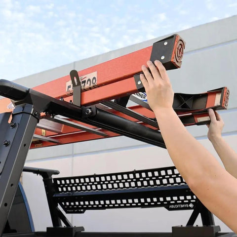 Person loading a ladder onto a truck roof rack using Built Tough 23.5 Inch Powder Coated Aluminum Ladder Roller.