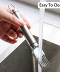 Side view of a stainless steel 2-piece scallion cutter held under running water in a kitchen sink.