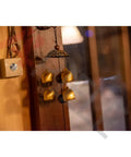 Interior view featuring golden wind chimes hanging near a wooden wall beside a square light switch with a metallic button.