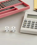 Upgrade Your 3D Printer With This Sweet Kit Of Six Gt2 Timing Belt Pulleys Featuring A Solid Aluminum Build And 20 Teeth Designed To Stop Slipping And Boost Power Transfer For Super Smooth Printing Plus Comes With A Hex Wrench For Easy Install. Two silver aluminum GT2 timing belt pulleys on a desk beside a calculator