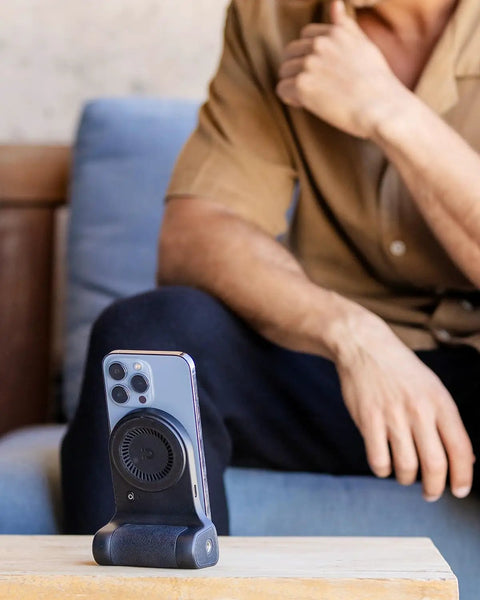 Magnetic Phone Stand Camera Grip With Wireless Charging And Bluetooth Shutter For iPhone on a table, ergonomic design for vlogging.