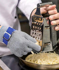 Chef grating cheese wearing A9 Cut Resistant Kitchen Glove With Food Grade Stainless Steel Wire Mesh For Knife Safety In Slicing Dicing Meat Oyster Shucking And Fish Fillet Heavy Duty Stainless Mesh Glove Chef-Grade Large Size 1 Piece.