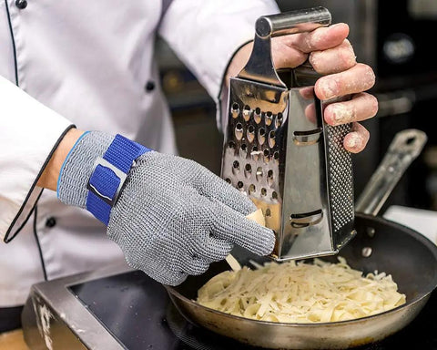 Chef grating cheese wearing A9 Cut Resistant Kitchen Glove With Food Grade Stainless Steel Wire Mesh For Knife Safety In Slicing Dicing Meat Oyster Shucking And Fish Fillet Heavy Duty Stainless Mesh Glove Chef-Grade Large Size 1 Piece.