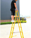 Heavy Duty Non Conductive Frp Telescoping Ladder Built Tough For Live Electrical Grind With Rock Solid Three Hundred Thirty Pound Rating And Quick Foldaway Design For Easy Hauling. Man standing on top step of yellow FRP ladder.