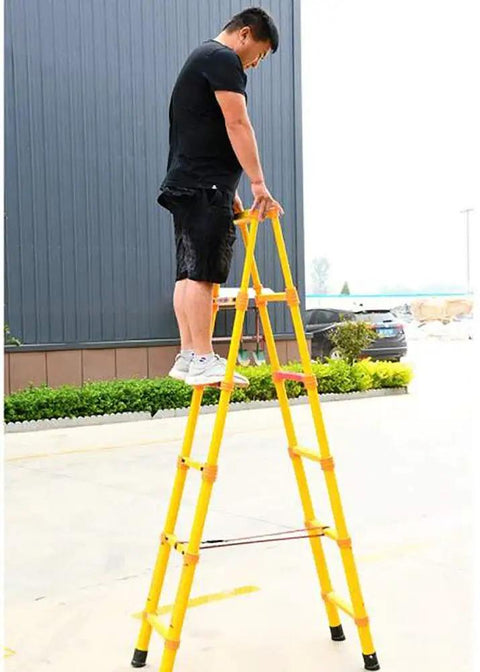 Heavy Duty Non Conductive Frp Telescoping Ladder Built Tough For Live Electrical Grind With Rock Solid Three Hundred Thirty Pound Rating And Quick Foldaway Design For Easy Hauling. Man standing on top step of yellow FRP ladder.