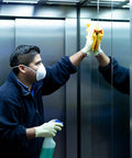 Man in mask cleaning elevator mirrors using Heavy Duty All Purpose Cleaner And Degreaser One Gallon Hella Effective At Cutting Through Grease Grime And Gunky Buildup For Kitchen Countertops Appliances Walls Cabinets And Floors Works Like Butter Daily.