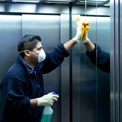 Man in mask cleaning elevator mirrors using Heavy Duty All Purpose Cleaner And Degreaser One Gallon Hella Effective At Cutting Through Grease Grime And Gunky Buildup For Kitchen Countertops Appliances Walls Cabinets And Floors Works Like Butter Daily.