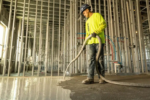 Worker applying No Sweat Setup Self Leveling Concrete Underlayment 50 Lb Bag for smooth interior flooring.