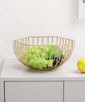 Golden Iron Fruit Basket For Fruits And Vegetables With Draining Water Feature And Geometric Wire Design Stackable Storage Organizer For Kitchen And Bathroom Use holding green grapes on kitchen counter