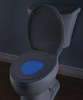 Sanborne Slow Close Round Toilet Seat With Built In Child Seat And Nightlight Soft Close Round Toilet Seat For Potty Training White 823902 N WH With A Removable Child Training Seat And Night Light Glow For Late Night Visits showing glowing nightlight in a dark bathroom.