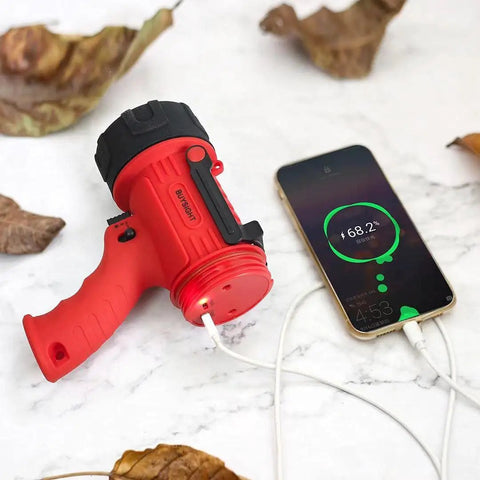 Rechargeable Handheld Spotlight Flashlight 200000 Lumens, Waterproof IP67 Hunting Lamp charging a phone outdoors on leaves