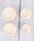 4pcs White Rubber Bathtub Stopper with Hanging Ring for Sink Drains in assorted sizes on a wood surface.